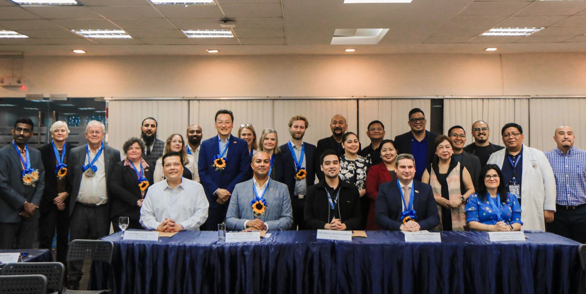 Table of five people sitting infront of 20 others at the MoU signing of the Twinning Partnership of Pasig City and West Yorkshire