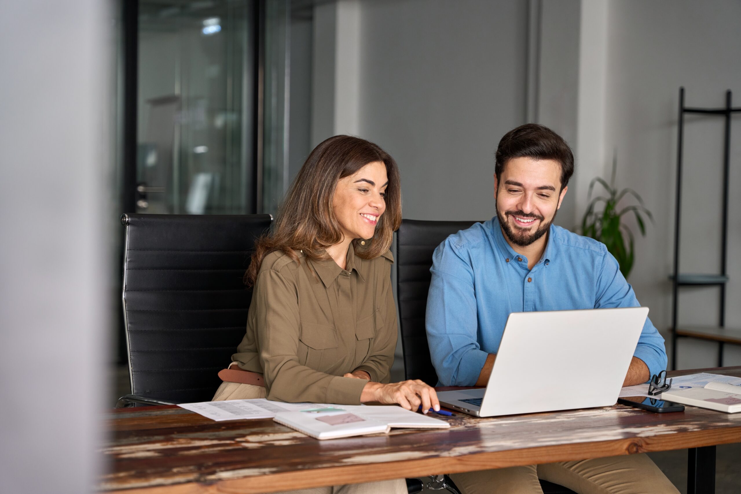 Two business people sitting at a desk together with a laptop